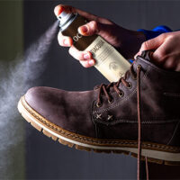 Dłonie spryskujące obuwie impregnatem do butów zamszowych Coccine