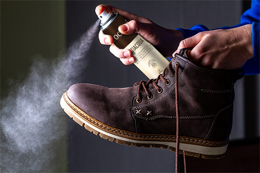 Dłonie spryskujące obuwie impregnatem do butów zamszowych Coccine